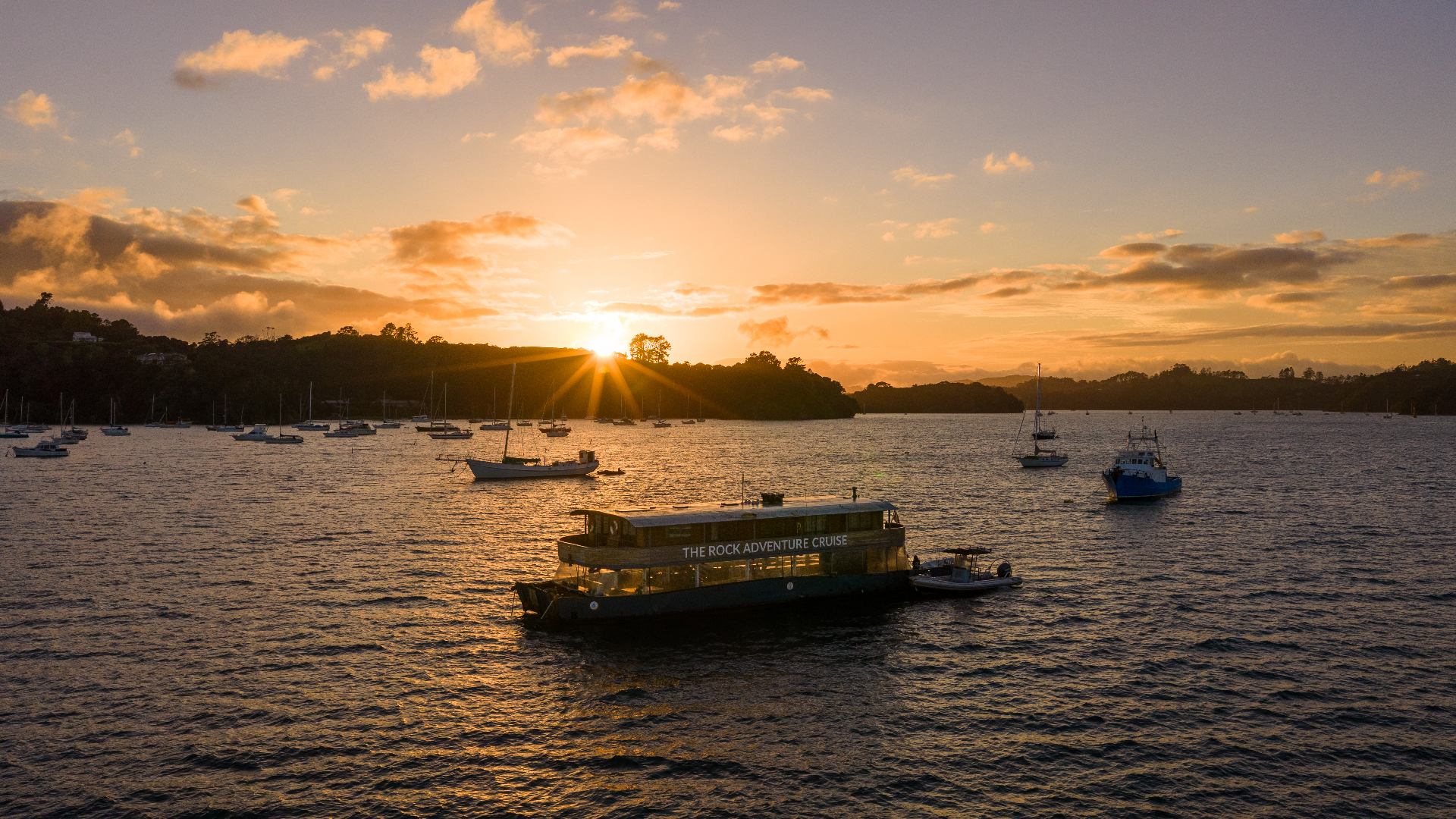 The Rock Adventure Cruise anchored in the Bay of Islands at golden sunset