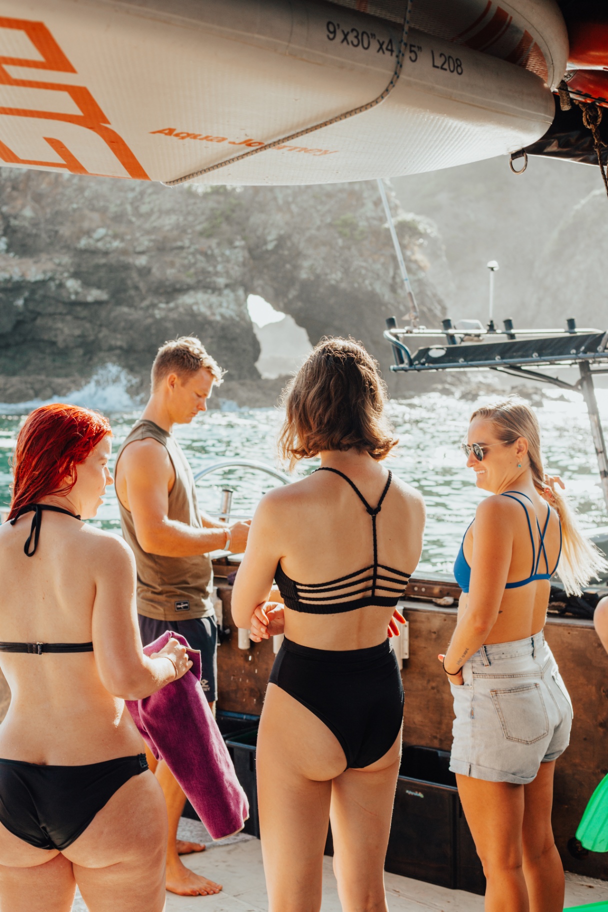 Group of friends paddleboarding off The Rock in the Bay of Islands