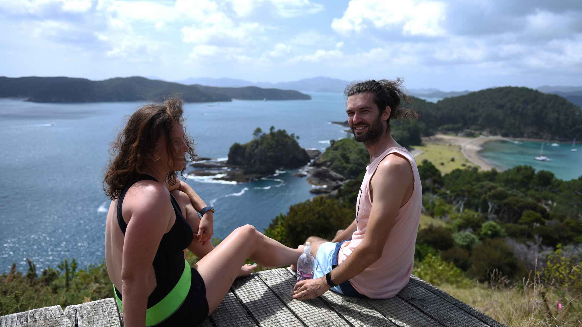 couple sitting at the top of roberton island, new zealand